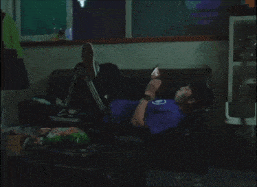 a man in a purple shirt with the word na on it looks at his phone