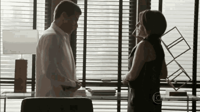 a man and a woman are standing in front of a window