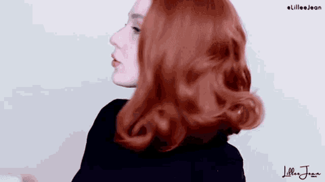 a woman with red hair is wearing a black dress and a black wig .