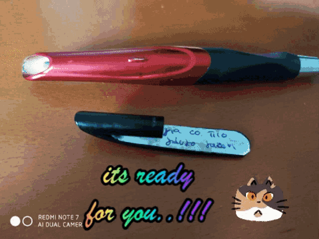 a red and black pen is on a wooden table with the words " it 's ready for you " below it