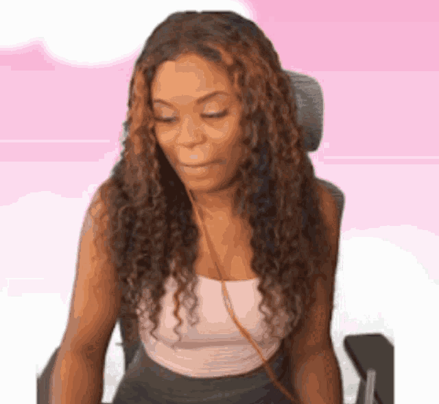 a woman with long curly hair is sitting in a chair