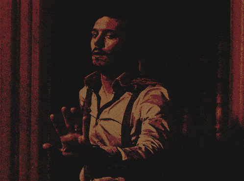 a man in a white shirt and suspenders stands in the dark