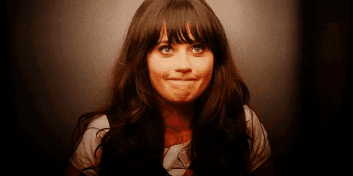 a woman with long hair and bangs is making a funny face and looking at the camera .