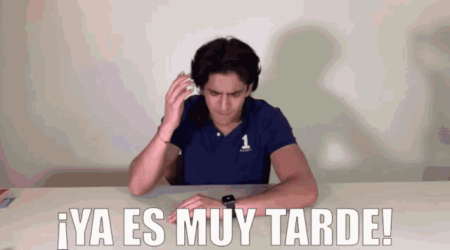 a man sitting at a table with the words ya es muy tarde written above him
