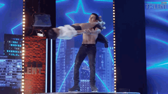 a man is holding another man up in the air on a stage that says talent on it