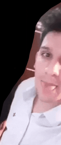 a man in a white shirt is taking a selfie with a black background .