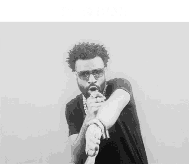 a man singing into a microphone with the words " i 'm bigger than i ever was " below him