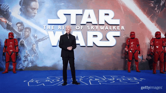 a man stands in front of a poster for star wars the rise of skywalker