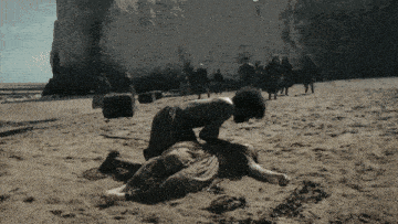 a man is kneeling on a woman laying on the beach