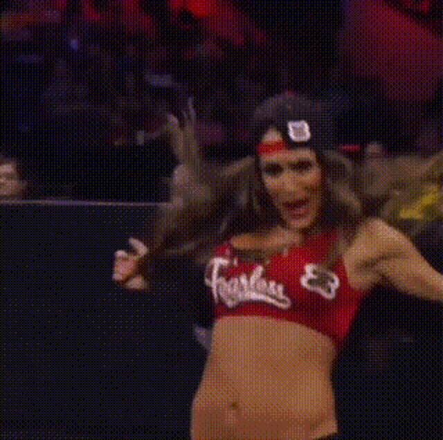 a woman in a red crop top and hat is dancing in a ring .