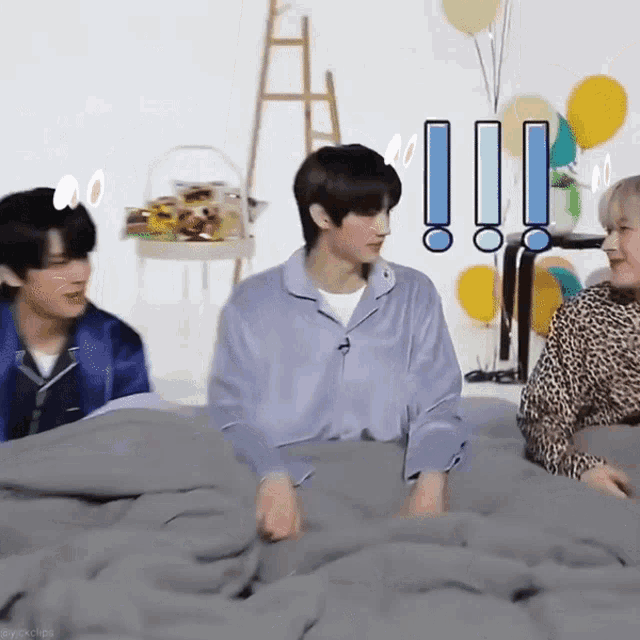 a group of young men are sitting on a bed with balloons in the background
