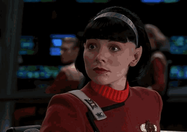 a woman in a red uniform has a badge on her shoulder that says x