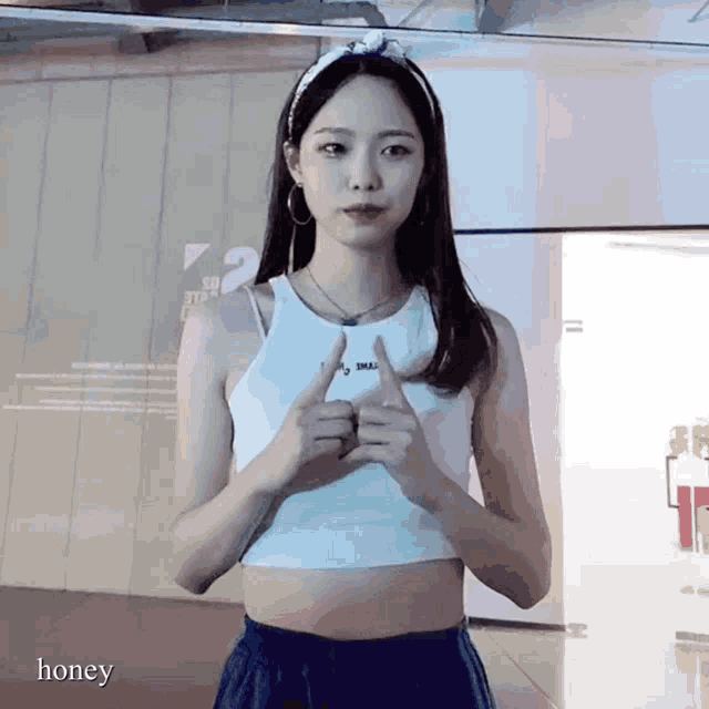 a woman wearing a white crop top and blue shorts is giving a thumbs up