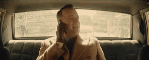 a man is sitting in the back seat of a car talking on a cell phone .