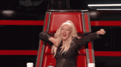 a woman is sitting in a red chair with her arms outstretched and smiling .