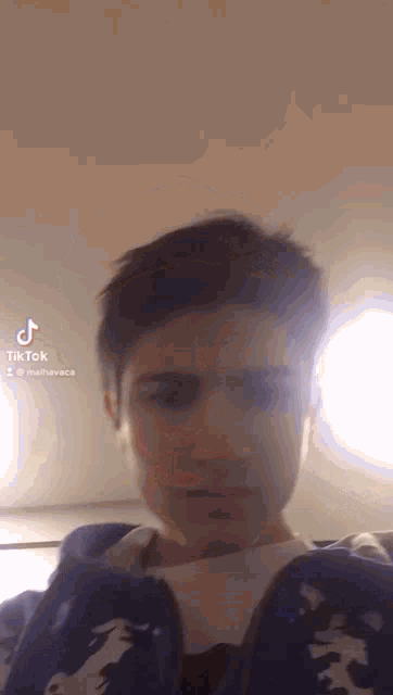 a young man wearing a blue jacket is taking a selfie with his phone .