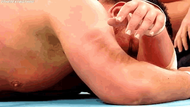 a man is laying on a blue mat with his head down and his hands on his face .