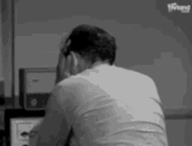 a man is sitting at a desk with his head in his hands and looking at a computer screen .