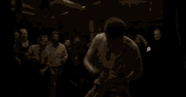 a shirtless man is dancing in front of a crowd of people