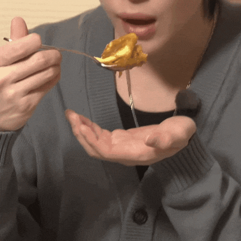 a person is holding a spoon in their hand and eating food