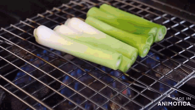a bunch of green onions are being cooked on a grill and the words made in animotica are visible