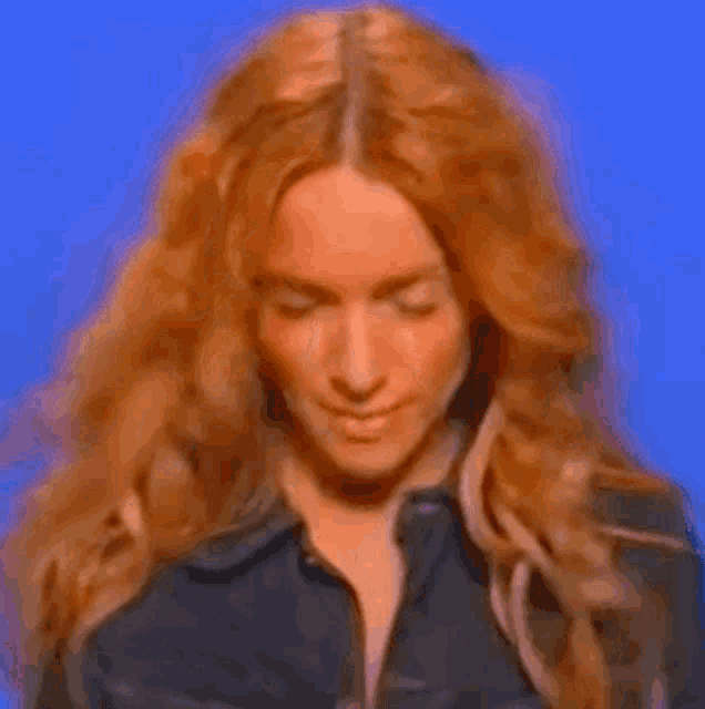 a close up of a woman with long red hair wearing a black jacket .