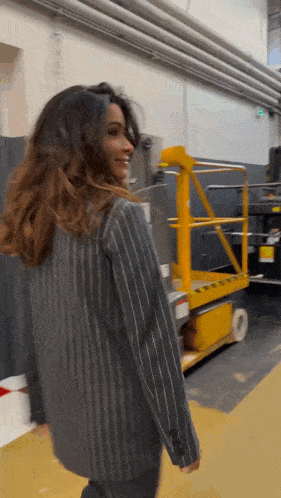 a woman in a striped jacket is standing in front of a yellow ladder