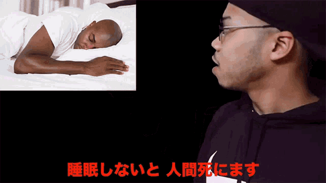 a man in a black nike hoodie looks at another man sleeping