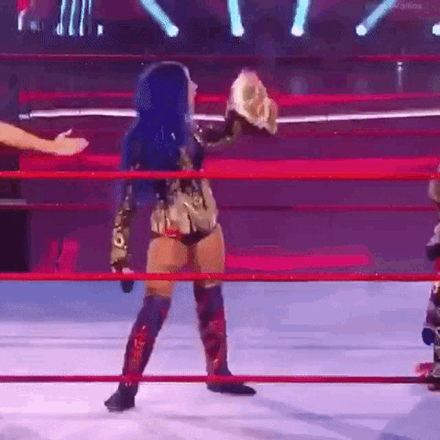 a woman in a wrestling ring is holding a trophy .
