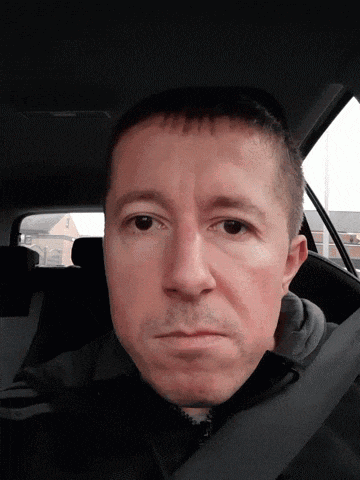 a man sitting in the back seat of a car making a face