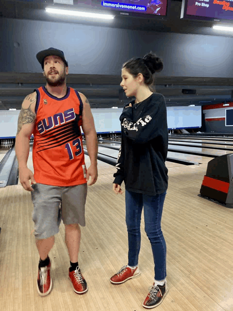 a man wearing an orange suns jersey is standing next to a woman
