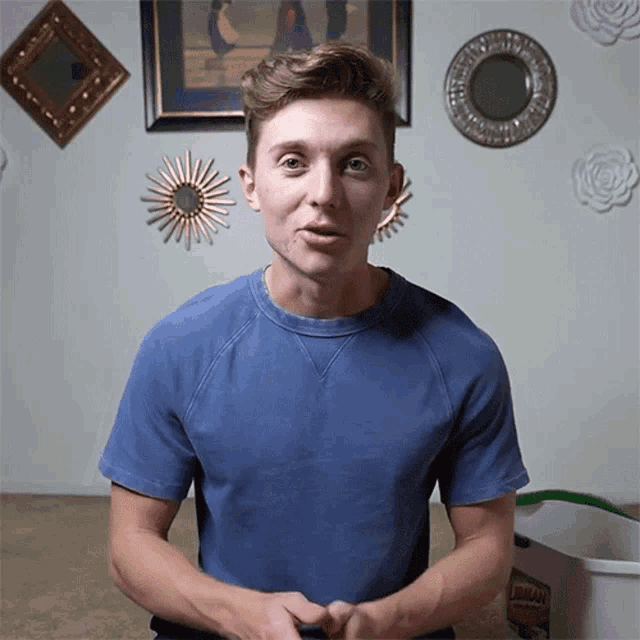 a man in a blue shirt is standing in front of a wall with mirrors and a can of ajax