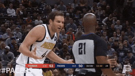 a basketball player in a pacers uniform talks to a referee