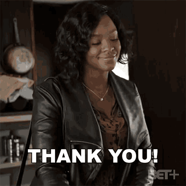 a woman in a leather jacket is smiling and says thank you