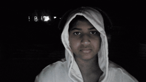 a person wearing headphones and a white hoodie with the time 8:17 on the clock behind them