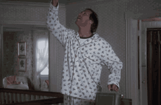a man in pajamas is holding a green suitcase and looking up