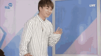 a young man in a striped shirt is standing in front of a blue wall .