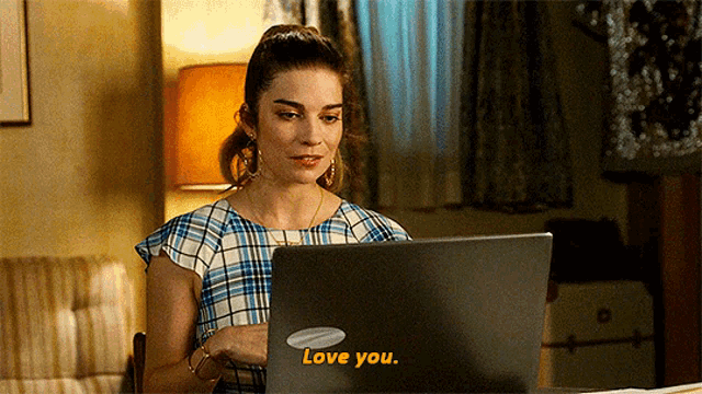 a woman sitting in front of a laptop with the words love you on the laptop