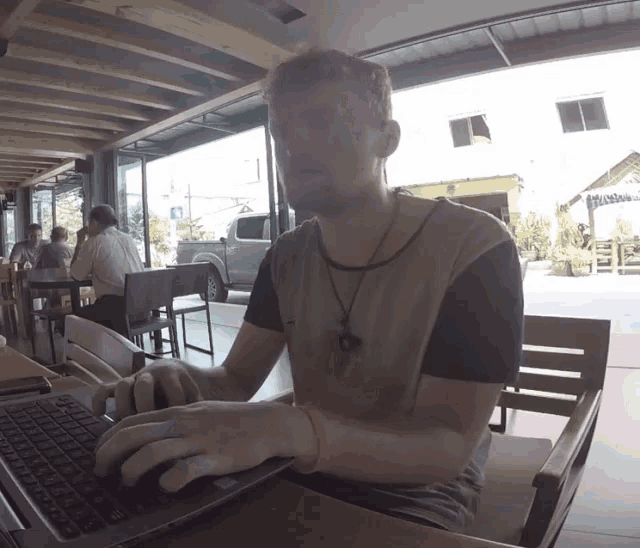 a man sits at a table typing on a laptop computer