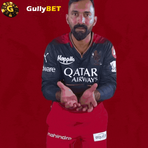 a man wearing a qatar airways jersey holds his hands out
