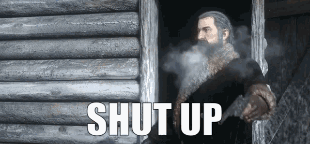 a man with a beard is holding a gun in front of a wooden wall with the words shut up on it .