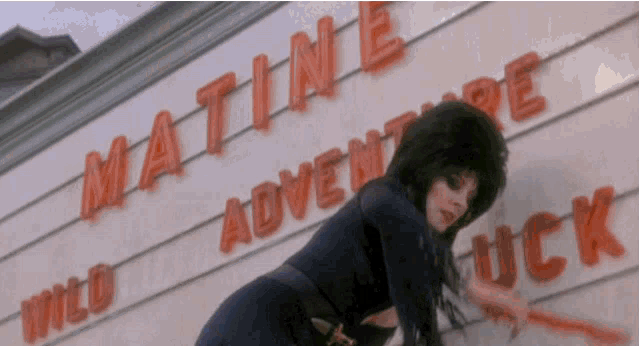a woman is standing in front of a sign that says matine adventure wild wild luck