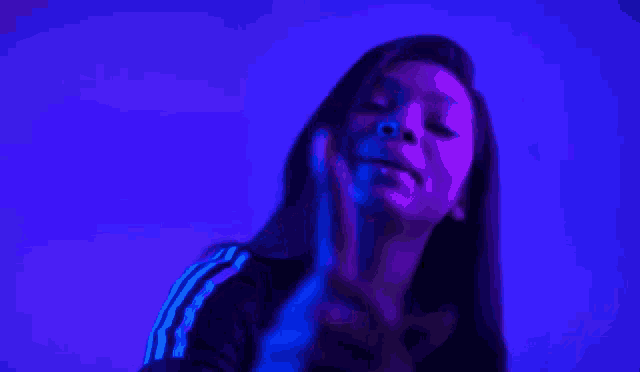 a woman is standing in front of a blue wall in a dark room .