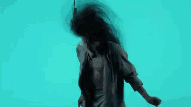 a woman with long hair is dancing in front of a blue background without a shirt on .