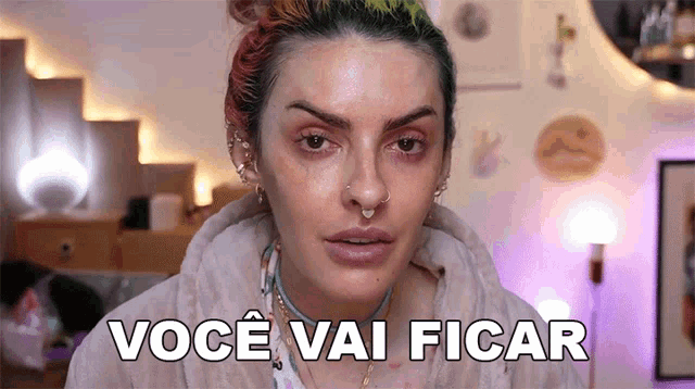a woman with a nose ring is making a funny face and saying você vai ficar