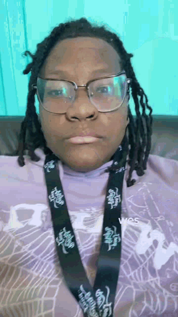 a woman with dreadlocks wearing glasses and a lanyard that says wes