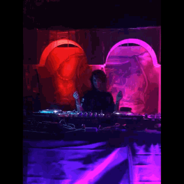a dj playing music in a dark room with a pioneer mixer