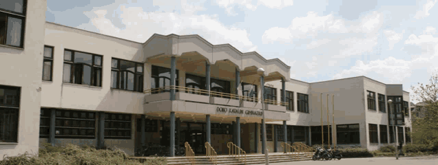 a large white building with a yellow sign that says ' soko aleksandra gymnasium ' on it