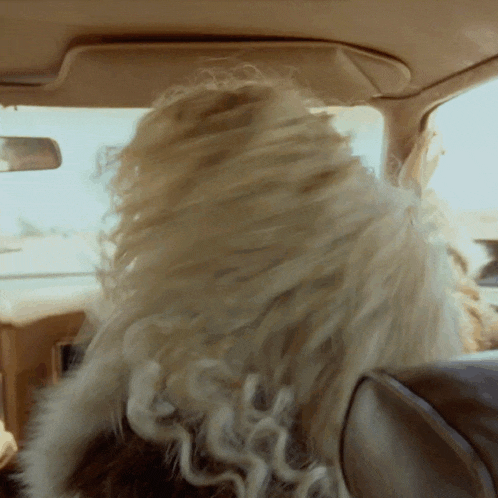 a woman with blonde hair is sitting in a car