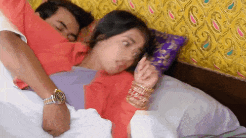 a man and a woman are laying on a bed with the man covering the woman 's face